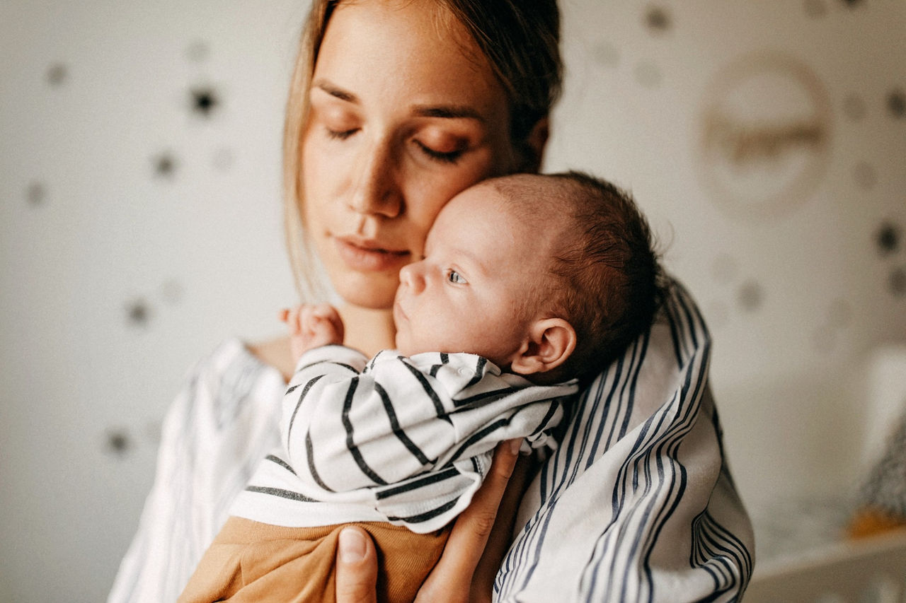 Junge Mutter hält Säugling im Arm