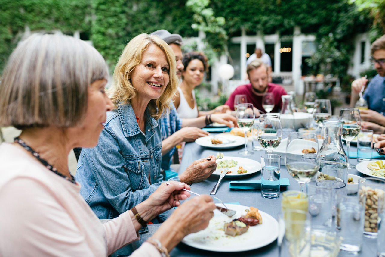 Mehrere Personen sitzen an einem Tisch im Freien und essen